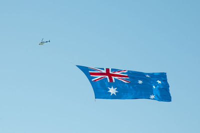 Low angle view of airplane flying against clear blue sky