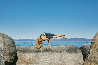 Young woman practicing yoga on lake tahoe in northern california.