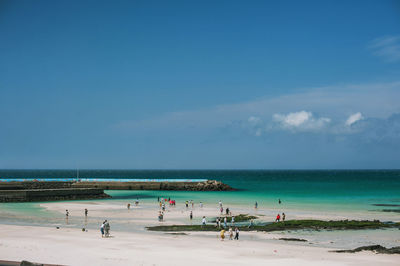 High angel view of people on beach against blue sky