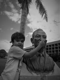 Portrait of boy holding statue nose in city