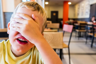 Boy shielding eyes while sitting at cafe