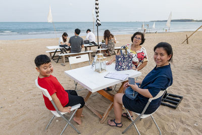 Friends sitting on table at beach