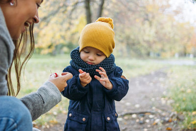 Woman with toddler son standing at park during autumn