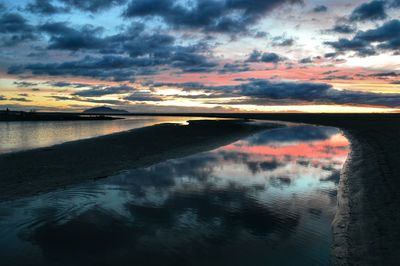 Scenic view of sea against cloudy sky at sunset