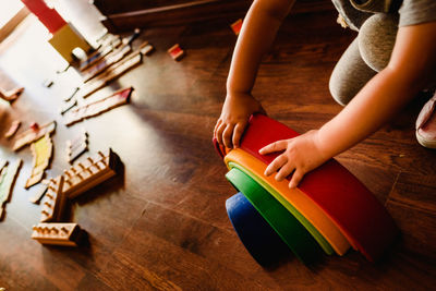 Low section of child playing with multi colored toys on hardwood floor