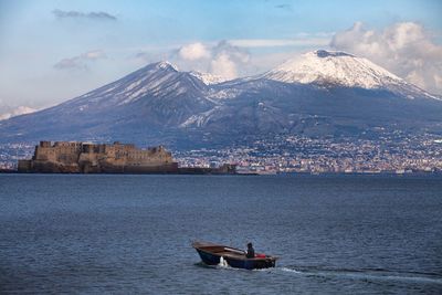 Scenic view of sea by snowcapped mountains against sky