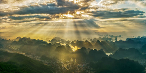 Sunlight streaming through clouds over landscape