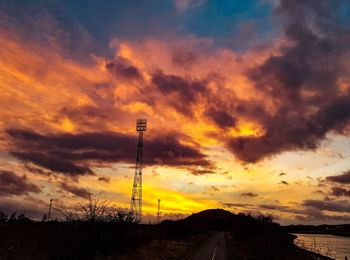 Silhouette road against dramatic sky during sunset