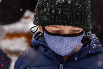 Portrait of boy in snow wearing a face mask