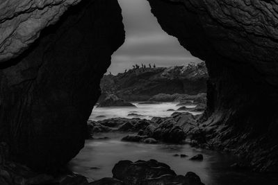 Rock formation on sea shore against sky