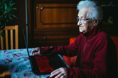 Smiling senior woman using laptop while sitting at home