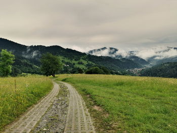 Road amidst field against sky