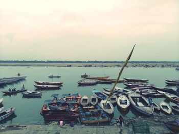 Fishing boats moored at harbor against sky