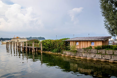 House by lake against sky