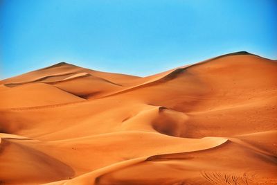 Sand dunes in desert against clear blue sky