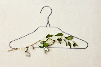 Iron hanger with trees sprig with leaves on linen background for eco-friendly, sustainable design. 