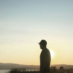 Silhouette of woman standing against sky at sunset