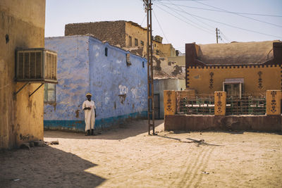 Rear view of man standing by old building against sky