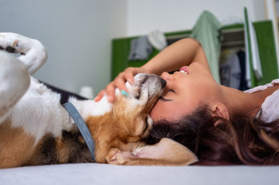 Girl with her eyes closed strokes her dog, pressing her head against his, while they both