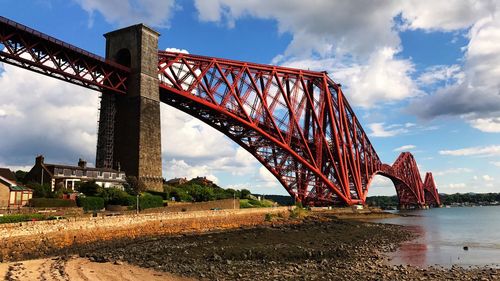 Low angle view of suspension bridge against cloudy sky