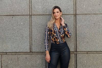 Woman looking away while standing against building