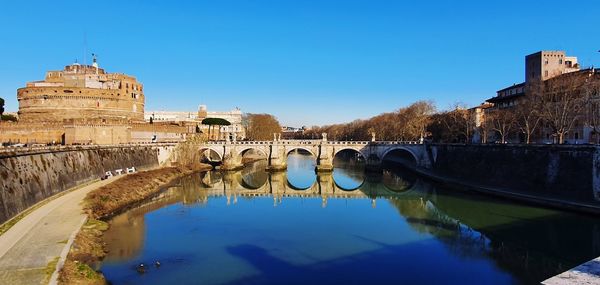 Arch bridge over river against blue sky