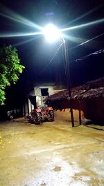 Illuminated street against sky at night