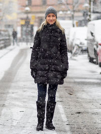 Portrait of smiling young woman standing in snow