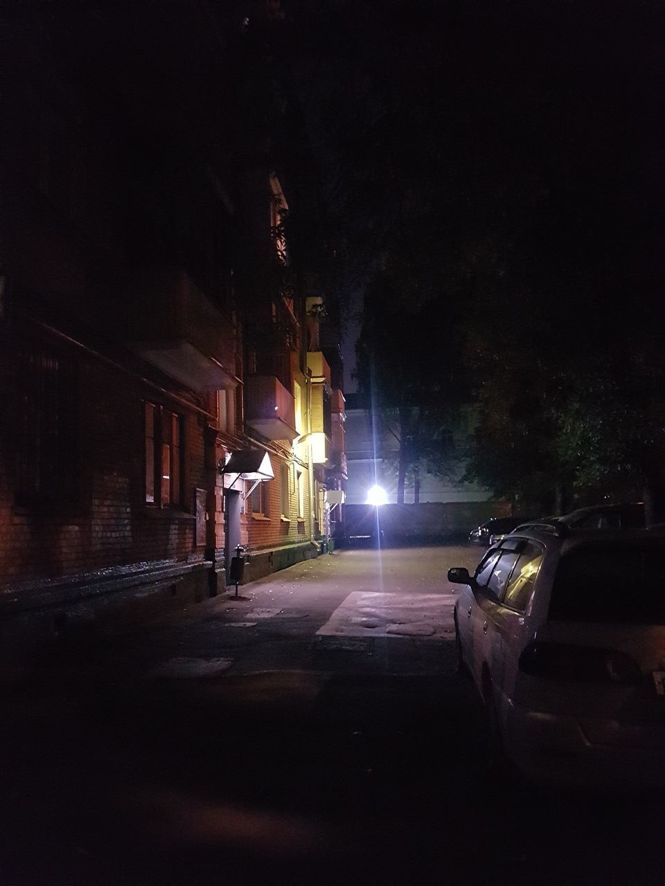 ILLUMINATED STREET AMIDST BUILDINGS AT NIGHT