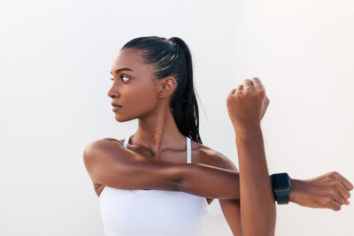 Portrait of young woman exercising against white background