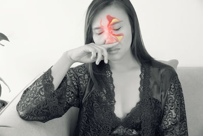 Portrait of young woman wearing mask standing against wall