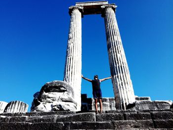 Low angle view of person standing against blue sky