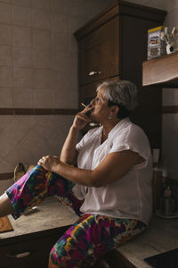 Woman smoking cigarette in kitchen