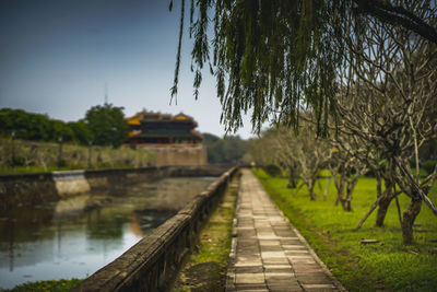 Footpath by lake against sky