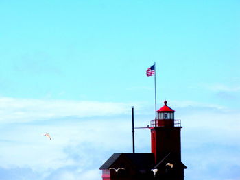 Red flag by lighthouse against sky