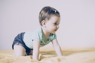 Cute boy looking away while relaxing on bed at home