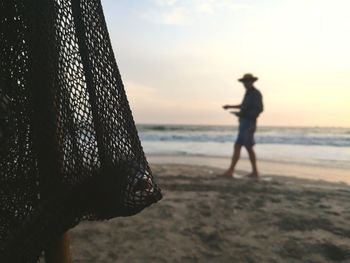 Silhouette person on beach against sky during sunset