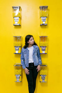 Young girl standing in front of a yellow wall with bubble gum machines