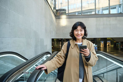 Portrait of young woman standing in city