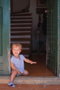 Portrait of cute baby boy sitting at entrance 