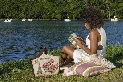 Rear view of woman sitting by lake