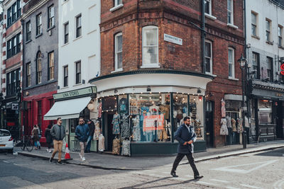 People walking on street amidst buildings in city