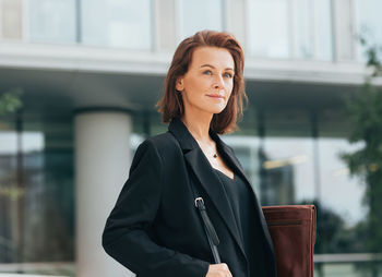 Portrait of young businesswoman standing in city