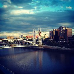 Bridge over river against cloudy sky