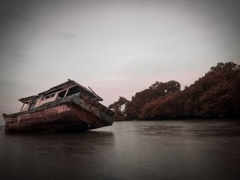 Abandoned built structure by lake against sky