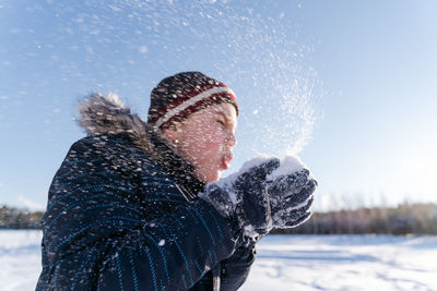 Boy blowing snow during winter