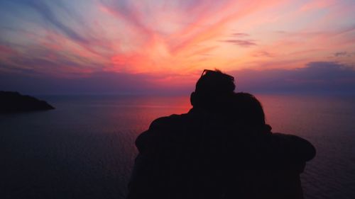 Silhouette couple against sea against sky during sunset