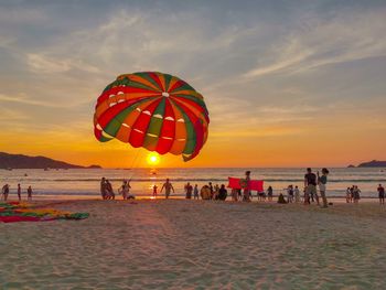 People at beach against sky during sunset