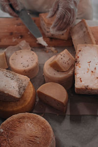 Man's hand with knife cutting a cheese on the wooden board. healthy eating and lifestyle.