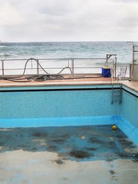 Swimming pool by sea against sky